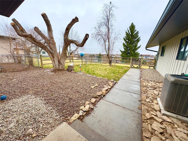view of yard with a gate, fence, and central AC