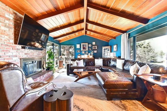 living area with a brick fireplace, lofted ceiling with beams, wood ceiling, and a healthy amount of sunlight