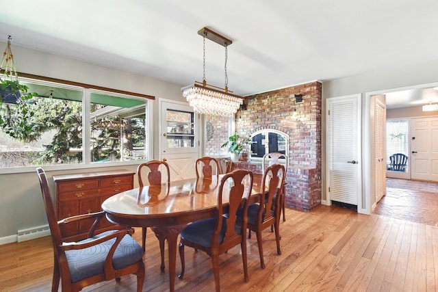 dining space featuring baseboards, baseboard heating, light wood-style flooring, and an inviting chandelier