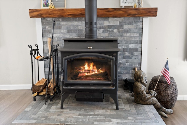 interior details with baseboards, a wood stove, and wood finished floors