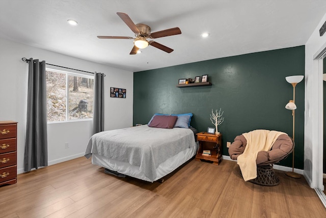 bedroom with recessed lighting, baseboards, wood finished floors, and an accent wall