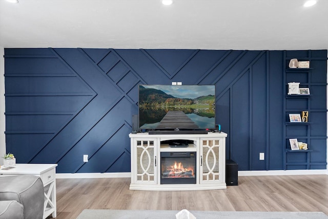 unfurnished living room with baseboards, recessed lighting, a decorative wall, and wood finished floors