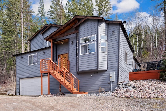 view of front of house with an attached garage, stairs, and dirt driveway