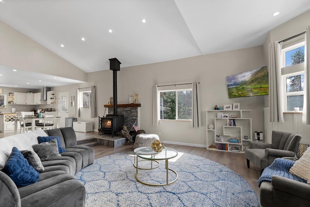 living room featuring recessed lighting, a wood stove, wood finished floors, and a wealth of natural light
