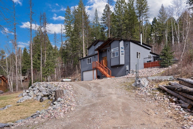 682 Latigo Ln, Bigfork, MT 59911 - view of front of home featuring driveway, stairs, an attached garage, and a view of trees