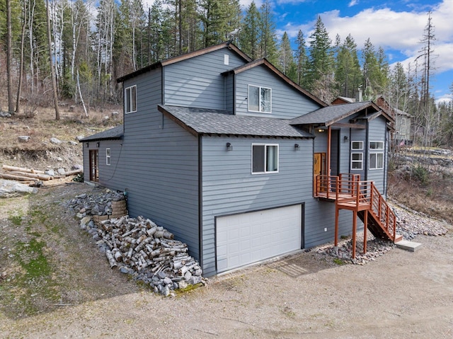 682 Latigo Ln, Bigfork, MT 59911 - view of front facade with a shingled roof, a garage, and dirt driveway