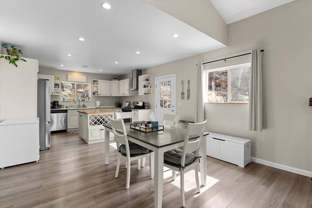 dining space featuring baseboards, light wood-type flooring, and recessed lighting