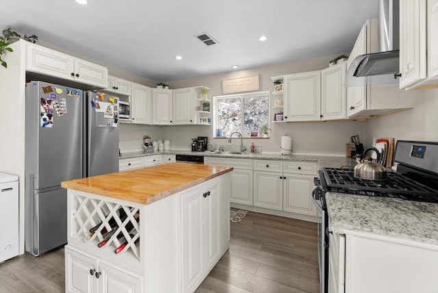 kitchen with open shelves, under cabinet range hood, a sink, wood counters, and appliances with stainless steel finishes