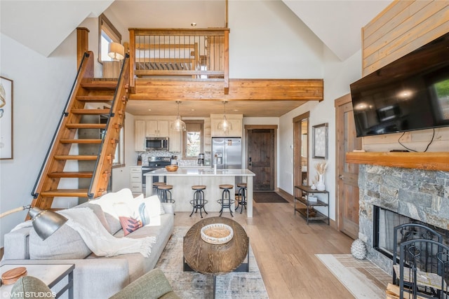 15 Haflinger Cottage Way, Eureka, MT 59917 - living area with high vaulted ceiling, stairs, light wood-type flooring, baseboards, and a stone fireplace