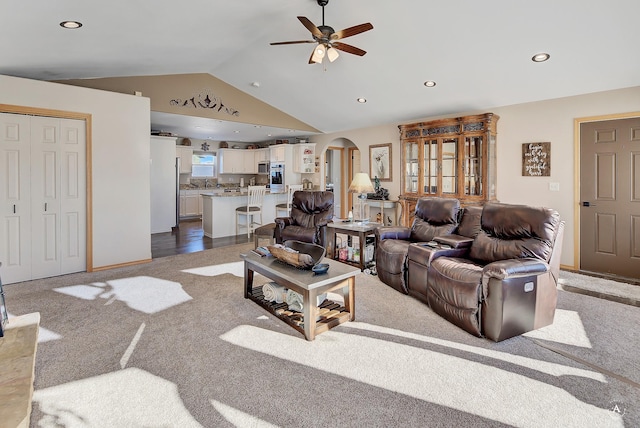 carpeted living room featuring baseboards, arched walkways, a ceiling fan, recessed lighting, and vaulted ceiling