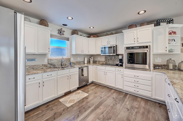 kitchen featuring light wood-style flooring, open shelves, white cabinets, appliances with stainless steel finishes, and a sink