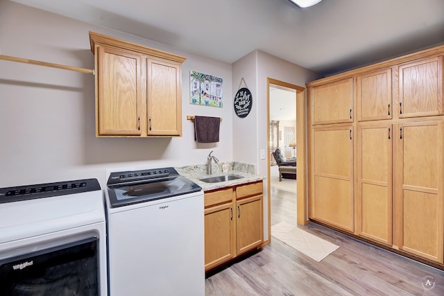 laundry area featuring light wood-style flooring, independent washer and dryer, a sink, and cabinet space