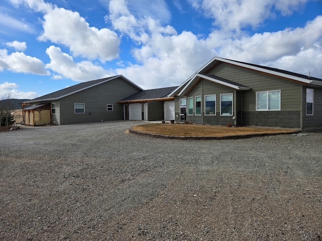 ranch-style home with an attached garage and dirt driveway