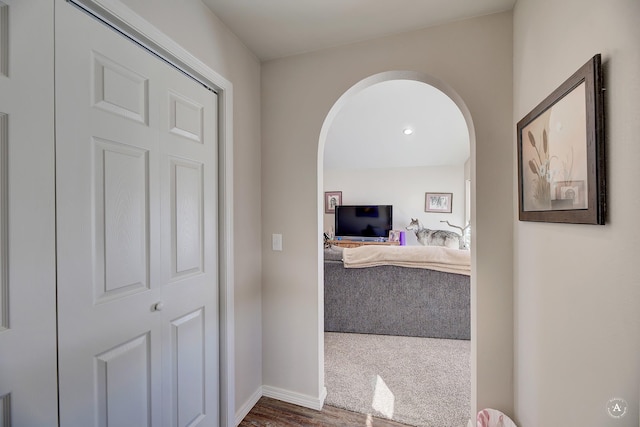 hallway featuring arched walkways and baseboards