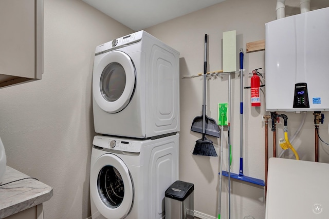 washroom featuring laundry area, stacked washer and clothes dryer, tankless water heater, and baseboards