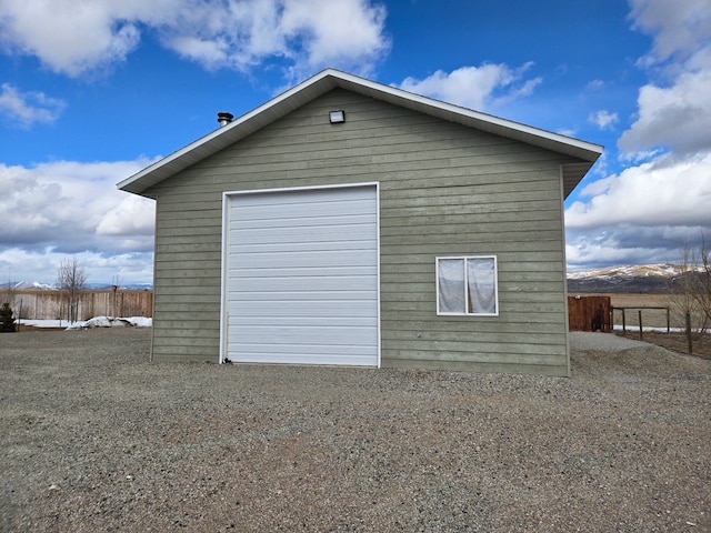 detached garage featuring driveway and fence