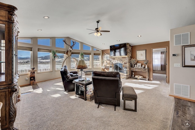 carpeted living room with visible vents, a ceiling fan, vaulted ceiling, and a fireplace