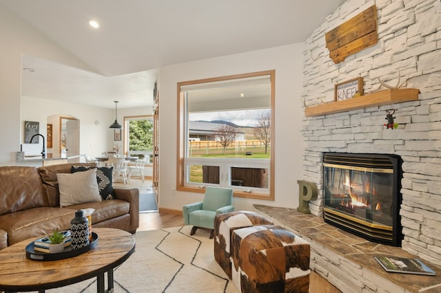 5632 Fairview Ln, Florence, MT 59833 - living room featuring vaulted ceiling, recessed lighting, arched walkways, a stone fireplace, and wood finished floors