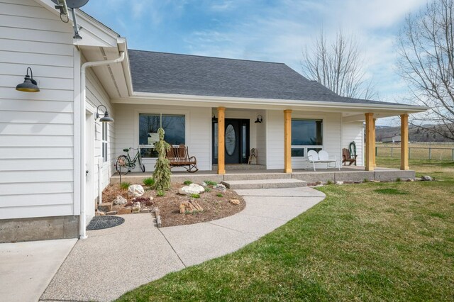 5632 Fairview Ln, Florence, MT 59833 - view of exterior entry with a shingled roof, a porch, and a yard