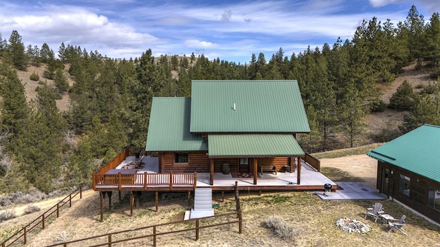 3340 Rome Ln, Stevensville, MT 59870 - rear view of house with log exterior, a wooden deck, a wooded view, and metal roof