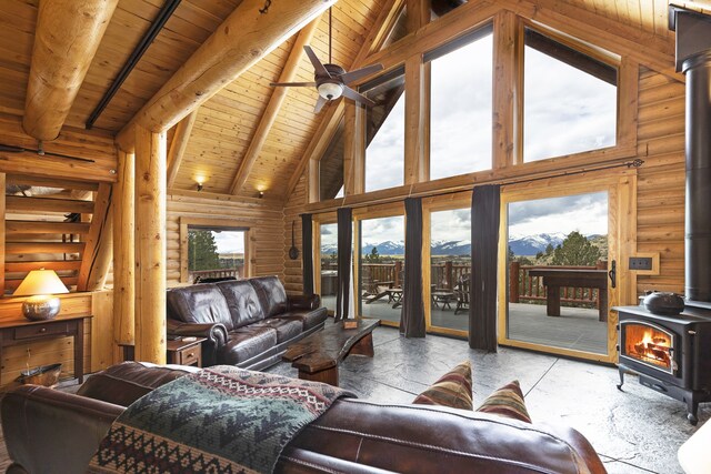3340 Rome Ln, Stevensville, MT 59870 - living room featuring a wood stove, high vaulted ceiling, wood ceiling with exposed beams, rustic walls, and a mountain view