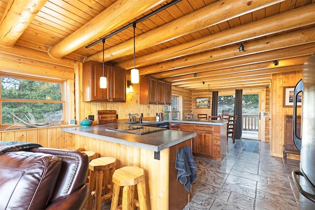 3340 Rome Ln, Stevensville, MT 59870 - kitchen featuring a peninsula, stone tile flooring, brown cabinetry, black electric cooktop, and wooden ceiling with exposed beams