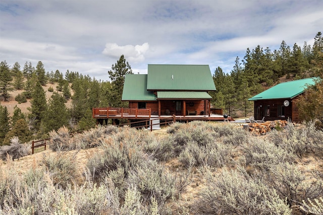 3340 Rome Ln, Stevensville, MT 59870 - rear view of property featuring a wooden deck, log siding, metal roof, and a view of trees