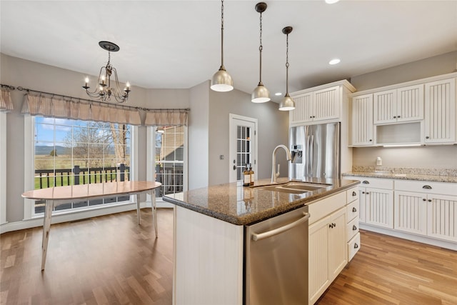 266 W Bowman Dr, Kalispell, MT 59901 - kitchen with dark stone counters, a sink, an island with sink, light wood-style flooring, and appliances with stainless steel finishes