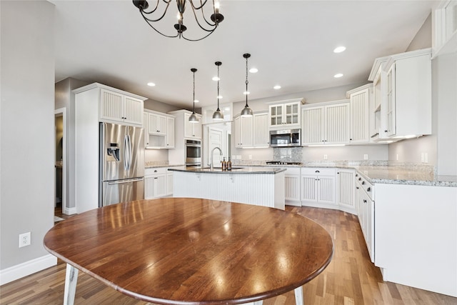 266 W Bowman Dr, Kalispell, MT 59901 - kitchen with a kitchen island with sink, a sink, light wood-style floors, glass insert cabinets, and appliances with stainless steel finishes