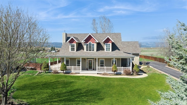 266 W Bowman Dr, Kalispell, MT 59901 - rear view of house with roof with shingles, a porch, a chimney, fence, and a lawn