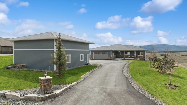 view of front of home featuring an attached garage, driveway, a front lawn, and a mountain view