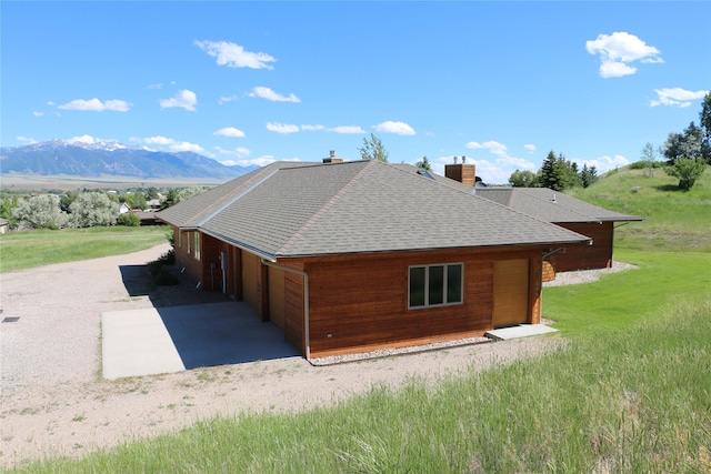 93 Golf Course Dr, Ennis, MT 59729 - view of side of home with roof with shingles, a chimney, a lawn, a mountain view, and gravel driveway