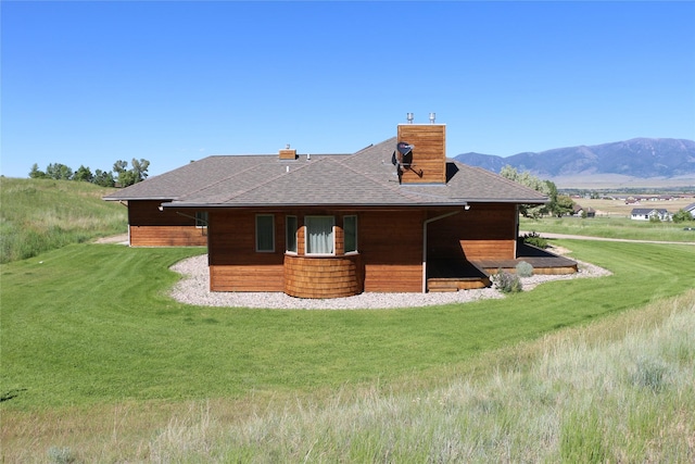 93 Golf Course Dr, Ennis, MT 59729 - back of property with a chimney, a shingled roof, a lawn, and a mountain view