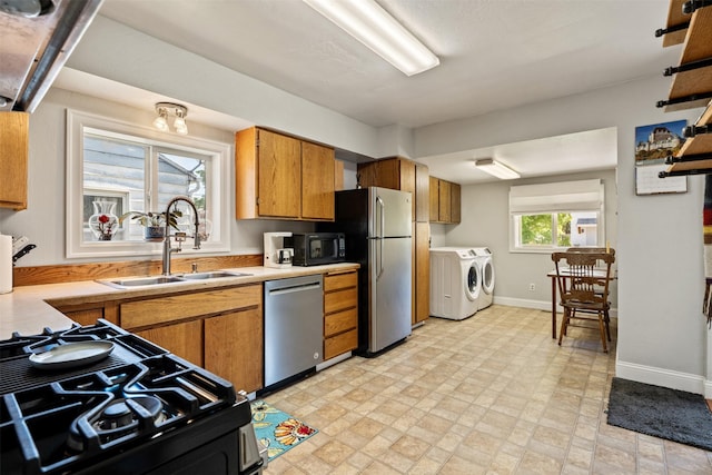 620 Stephens Ave, Missoula, MT 59801 - kitchen featuring washer and clothes dryer, a sink, black appliances, brown cabinetry, and light countertops