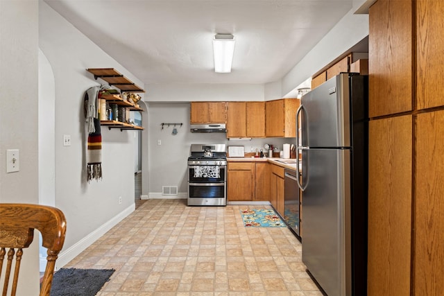 620 Stephens Ave, Missoula, MT 59801 - kitchen with appliances with stainless steel finishes, under cabinet range hood, brown cabinetry, baseboards, and light countertops