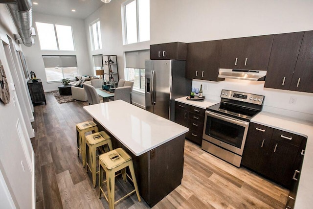 21D Hickory Loop, Whitefish, MT 59937 - kitchen featuring appliances with stainless steel finishes, under cabinet range hood, a kitchen breakfast bar, light wood-style floors, and light countertops