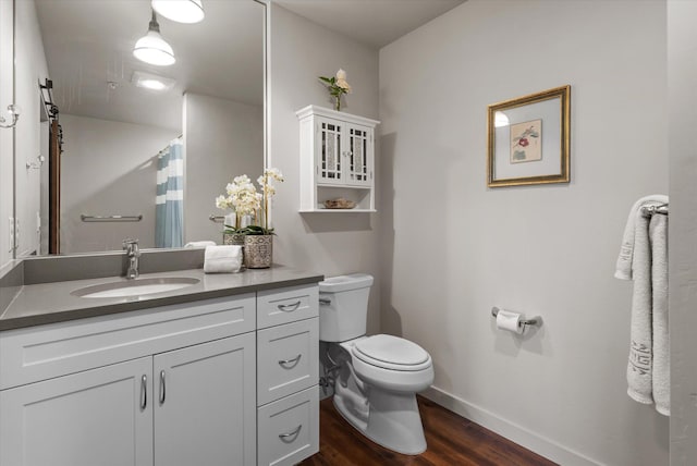 bathroom featuring toilet, vanity, wood finished floors, and baseboards
