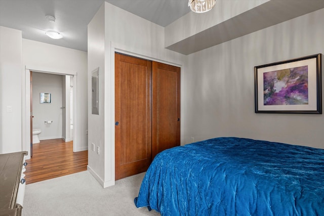 bedroom with a closet, light colored carpet, and baseboards