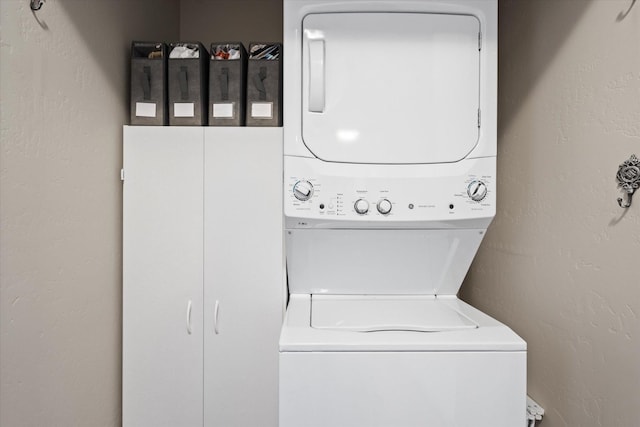 clothes washing area with a textured wall and stacked washer and dryer