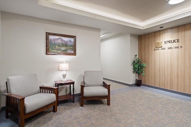 living area with a tray ceiling, baseboards, and carpet floors