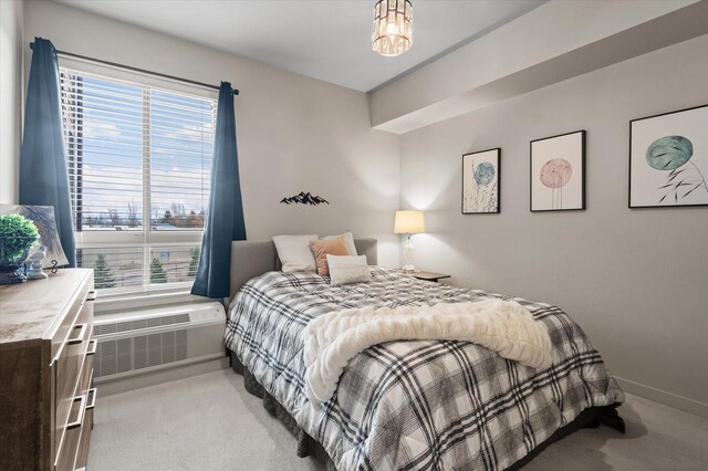 bedroom featuring baseboards, multiple windows, light colored carpet, and a wall mounted air conditioner
