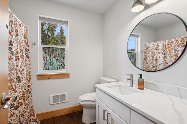bathroom with a wealth of natural light, visible vents, toilet, and wood finished floors