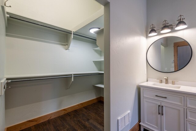bathroom with visible vents, baseboards, vanity, and wood finished floors