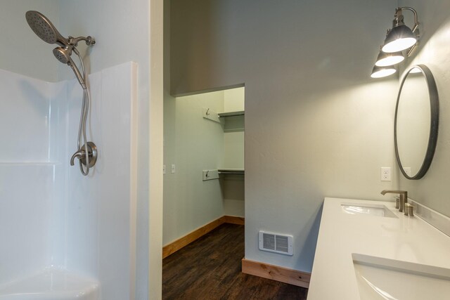 bathroom featuring a sink, visible vents, walk in shower, and wood finished floors