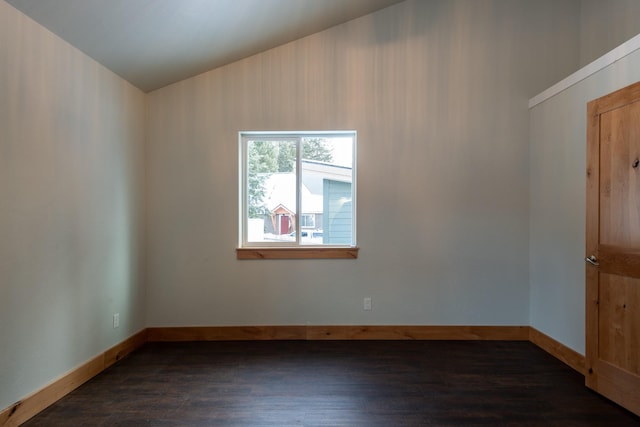 empty room with dark wood-style flooring, baseboards, and lofted ceiling