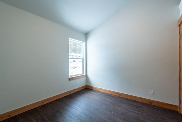 unfurnished room with dark wood-style flooring, baseboards, and lofted ceiling