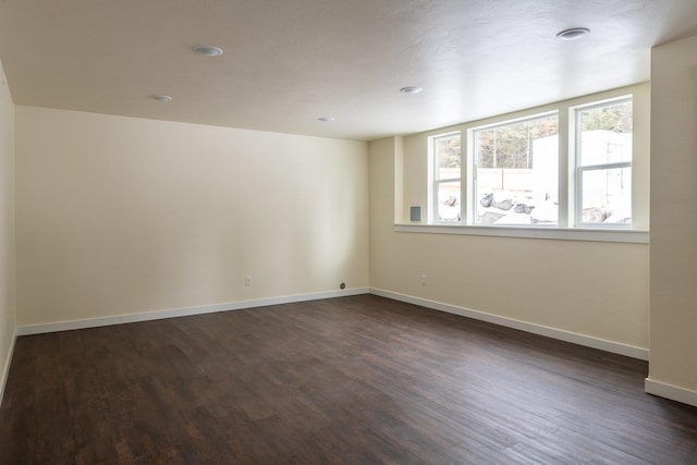 spare room with dark wood-style flooring and baseboards