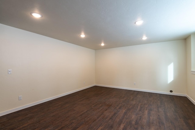 empty room with recessed lighting, dark wood-type flooring, and baseboards