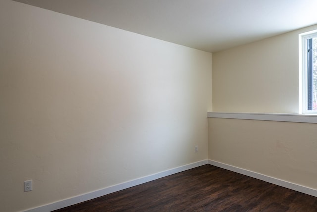 unfurnished room featuring dark wood-style flooring and baseboards