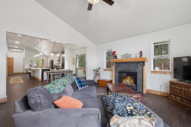 living room featuring ceiling fan, dark wood-style flooring, a tiled fireplace, and baseboards